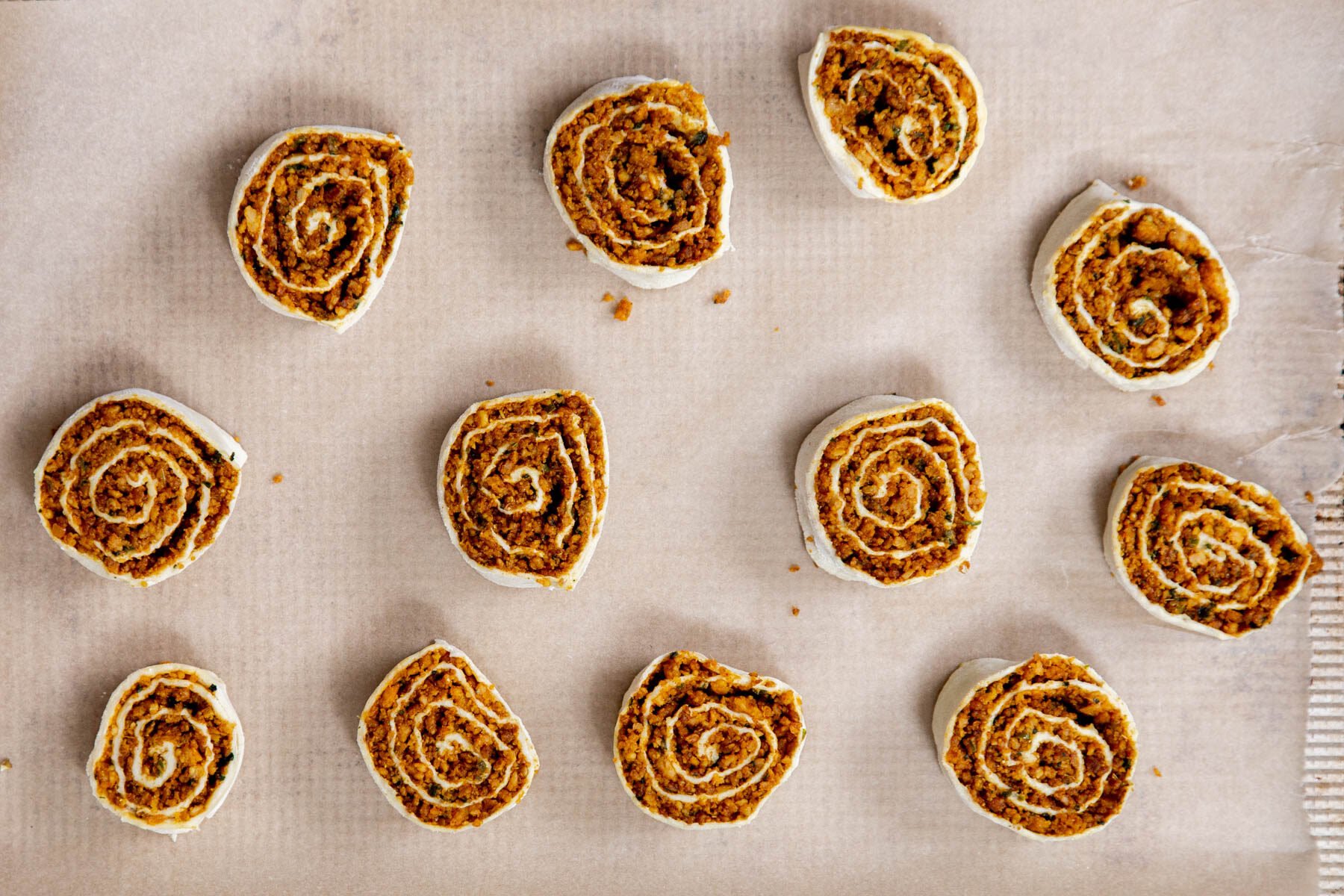 vegan pinwheels on a sheet of parchment paper ready for baking