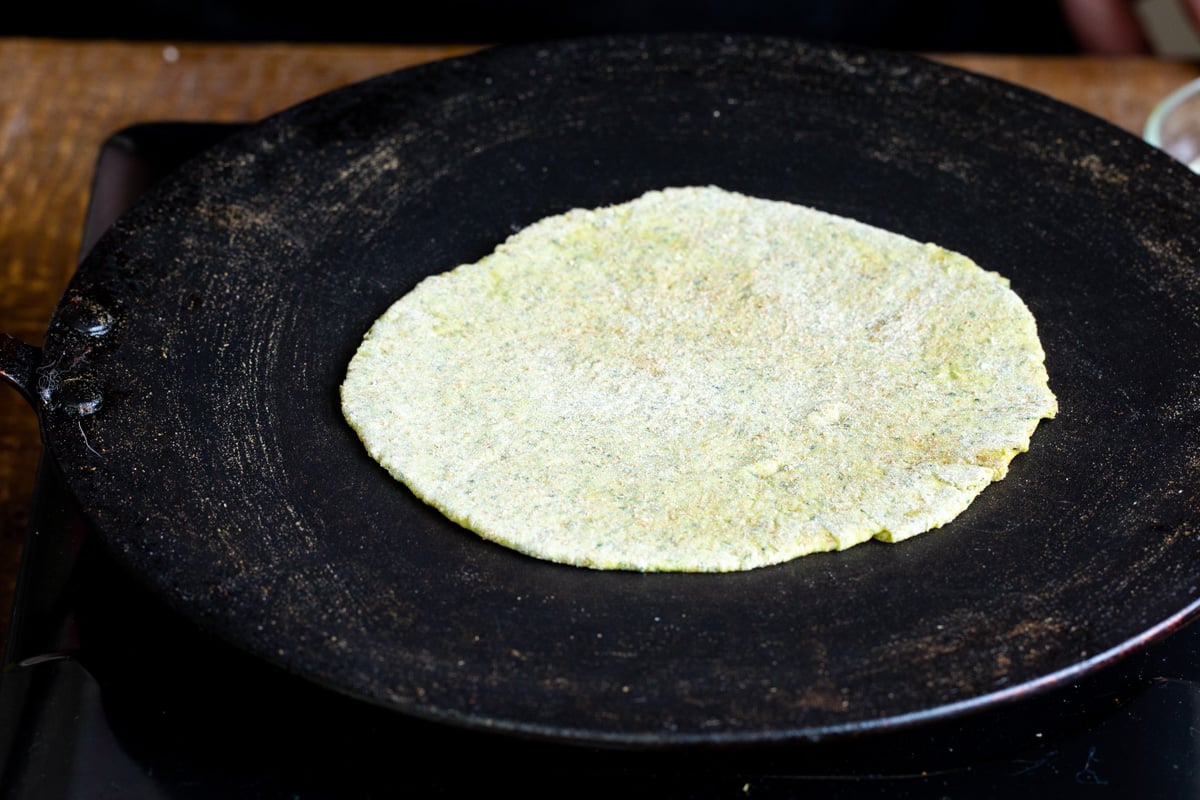 a masala paratha being toasted in a flat skillet