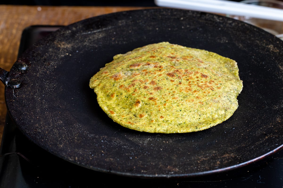 a freshy baked masala paratha on a black skillet