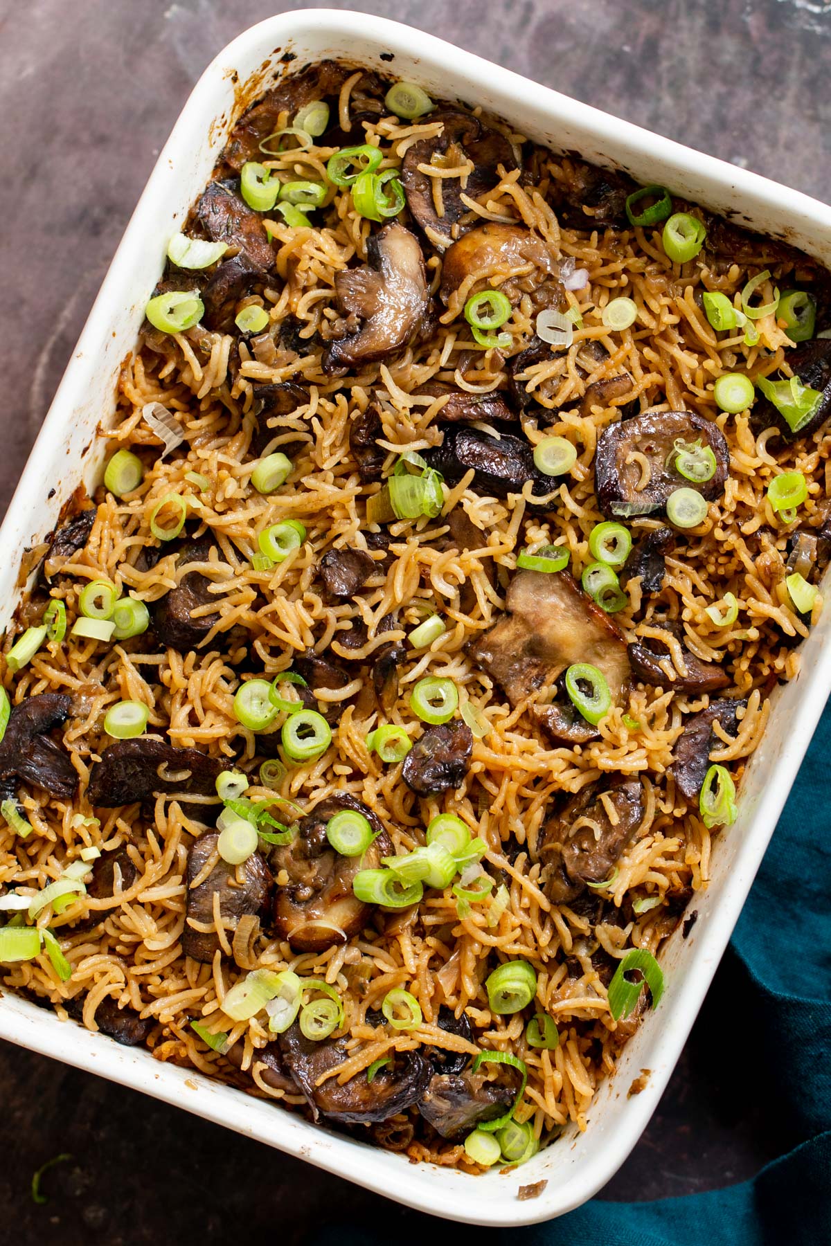 a casserole dish with baked mushroom rice sprinkled with sliced green onions