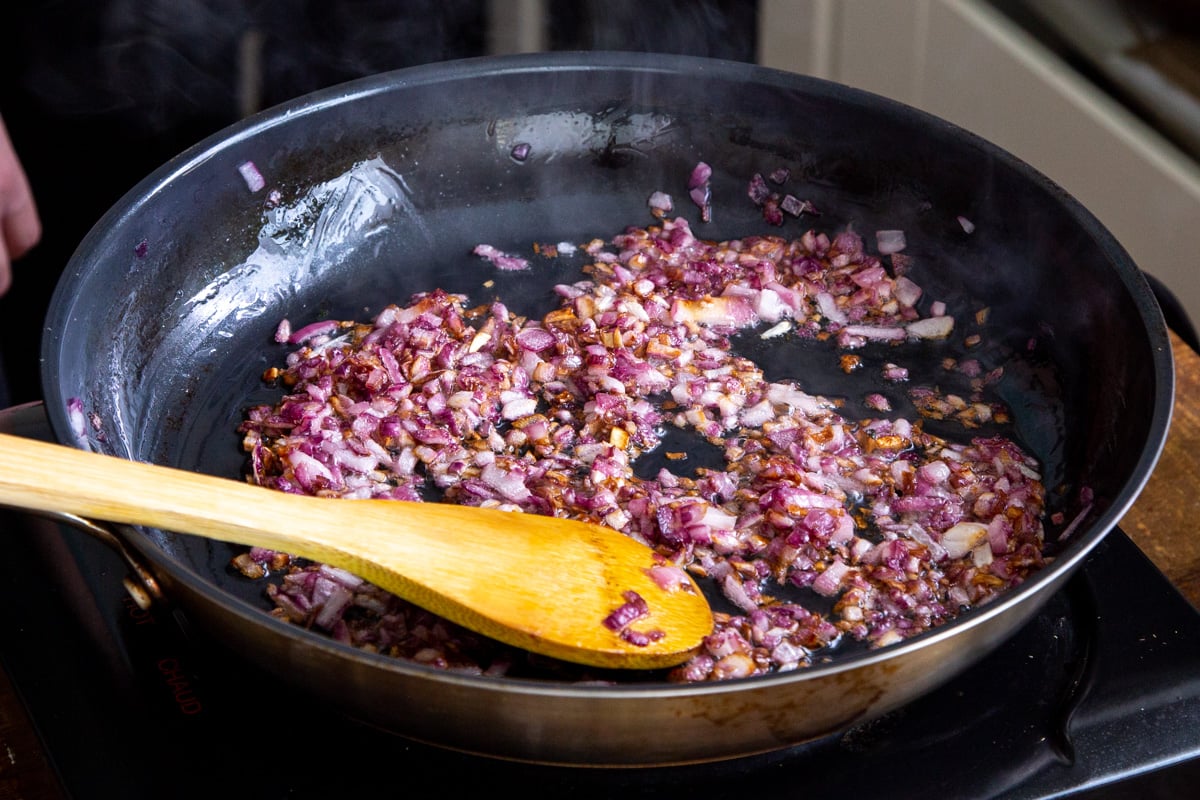 diced onion and spices frying in a sauteeing pan