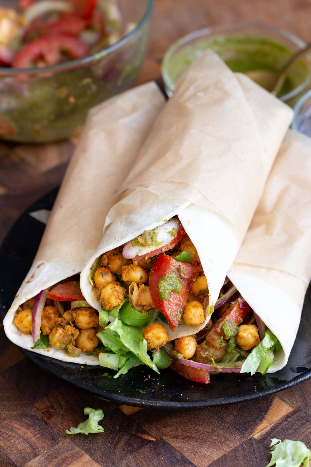 three Chana kathi rolls on a black plate