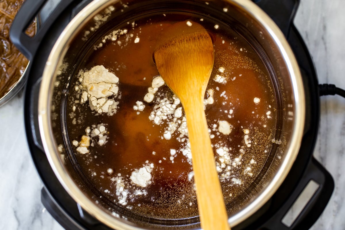 broth and flour being added to an Instant Pot to make vegan French Onion Soup