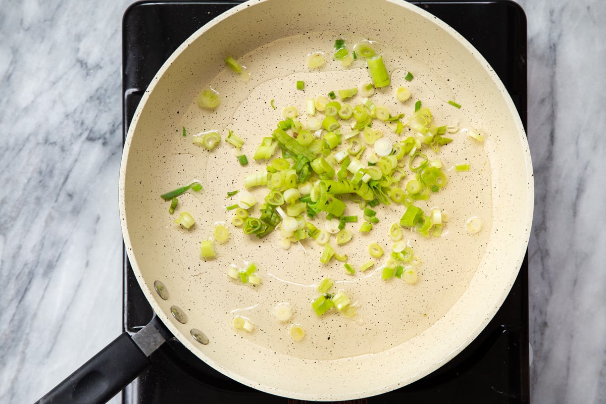 sliced green onions in a sauteeing pan
