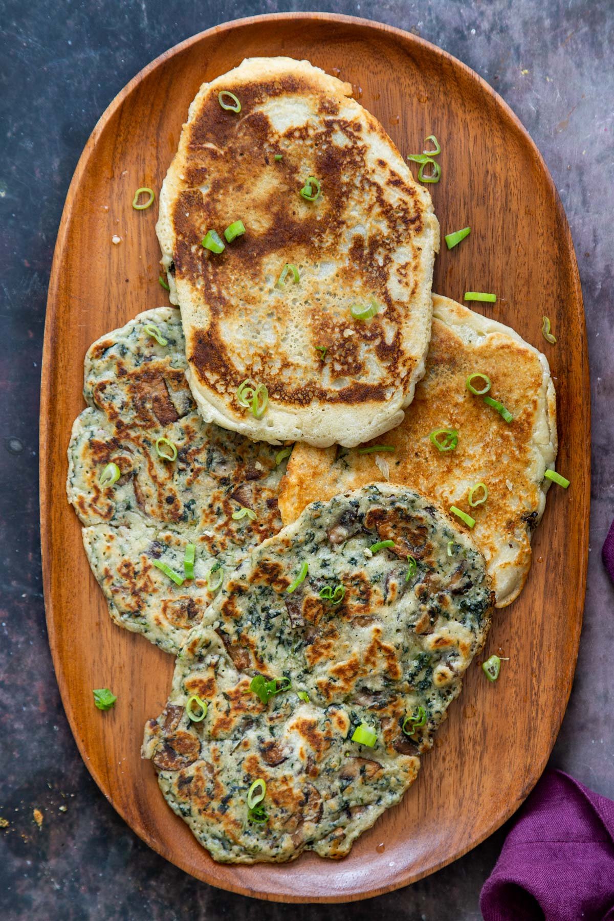 a wooden plate with 4 spinach mushroom naan breads