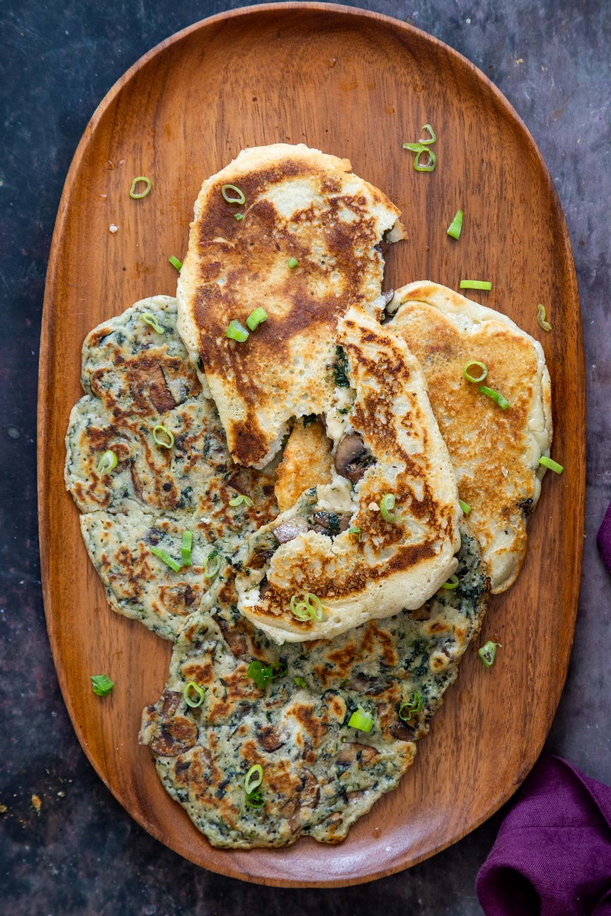 Glutenfree Vegan Spinach Mushroom Naan served in a wooden plate sprinkled with chopped green onions