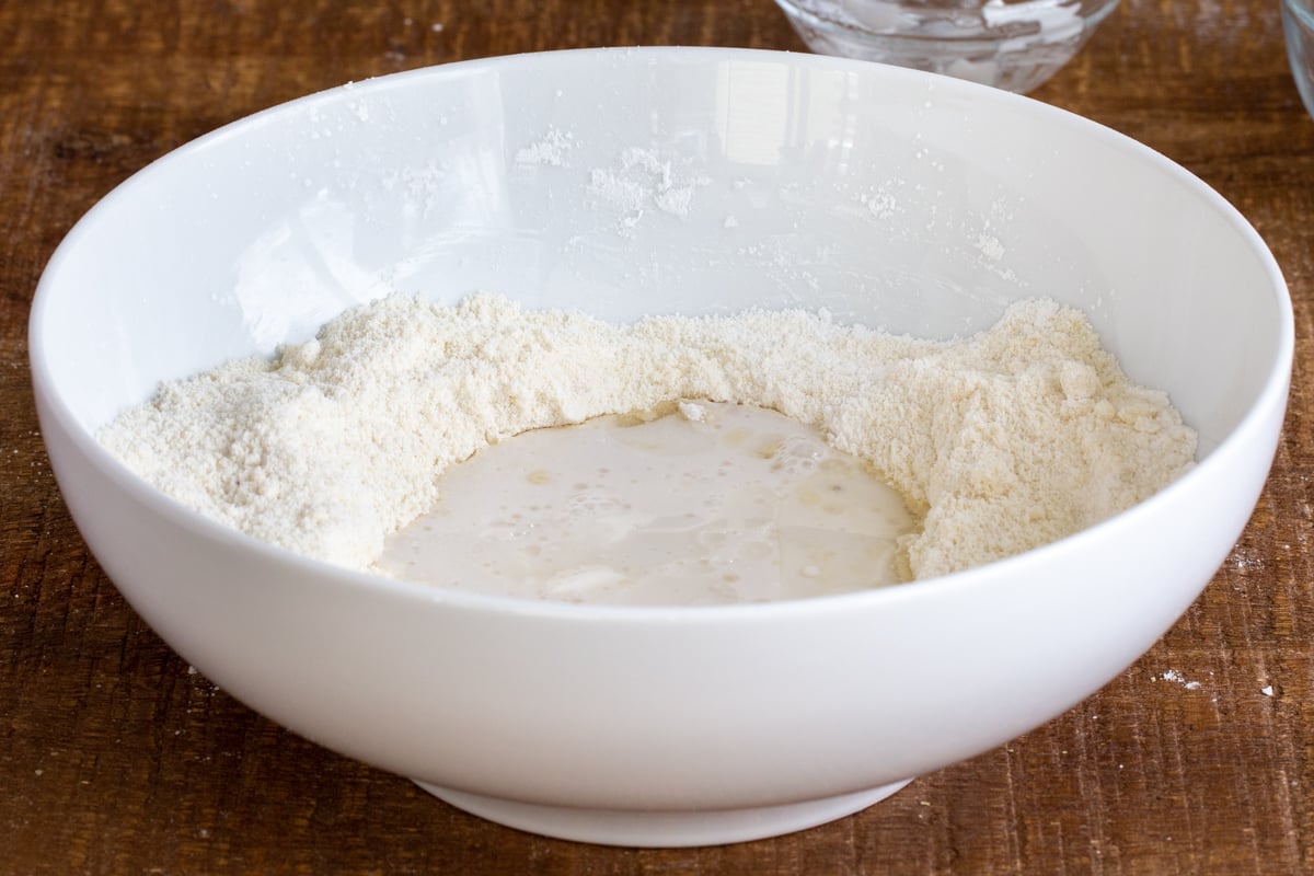 wet ingredients being added to dry ingredients in a white bowl