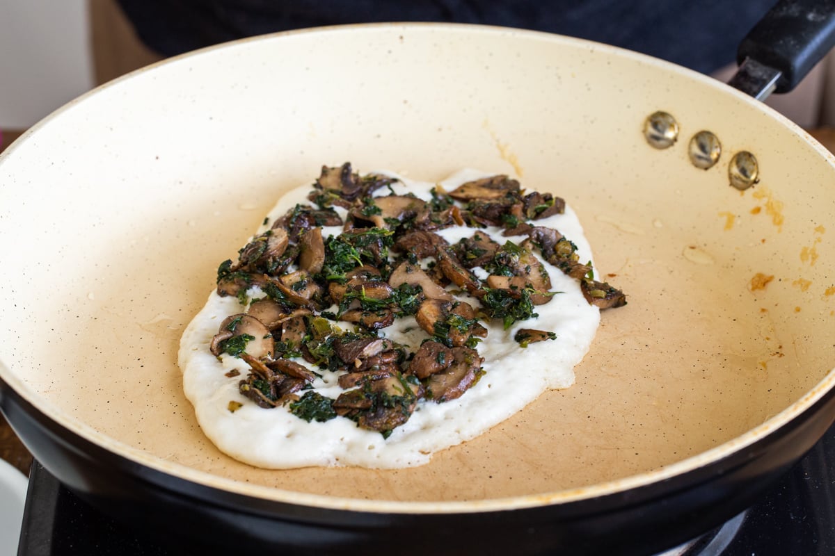 almond flour naan batter in a pan topped with mushrooms and spinach
