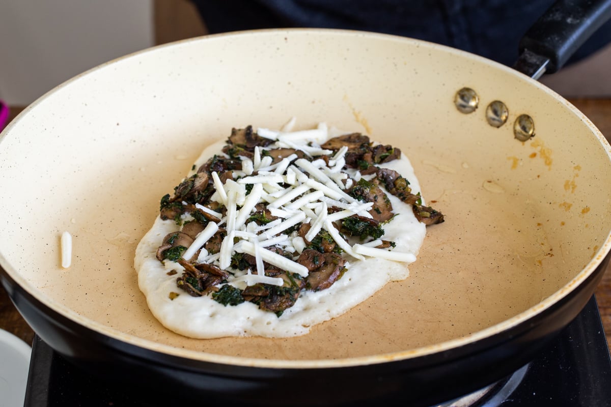 almond flour naan baking in a pan topped with mushrooms and spinach and cheese