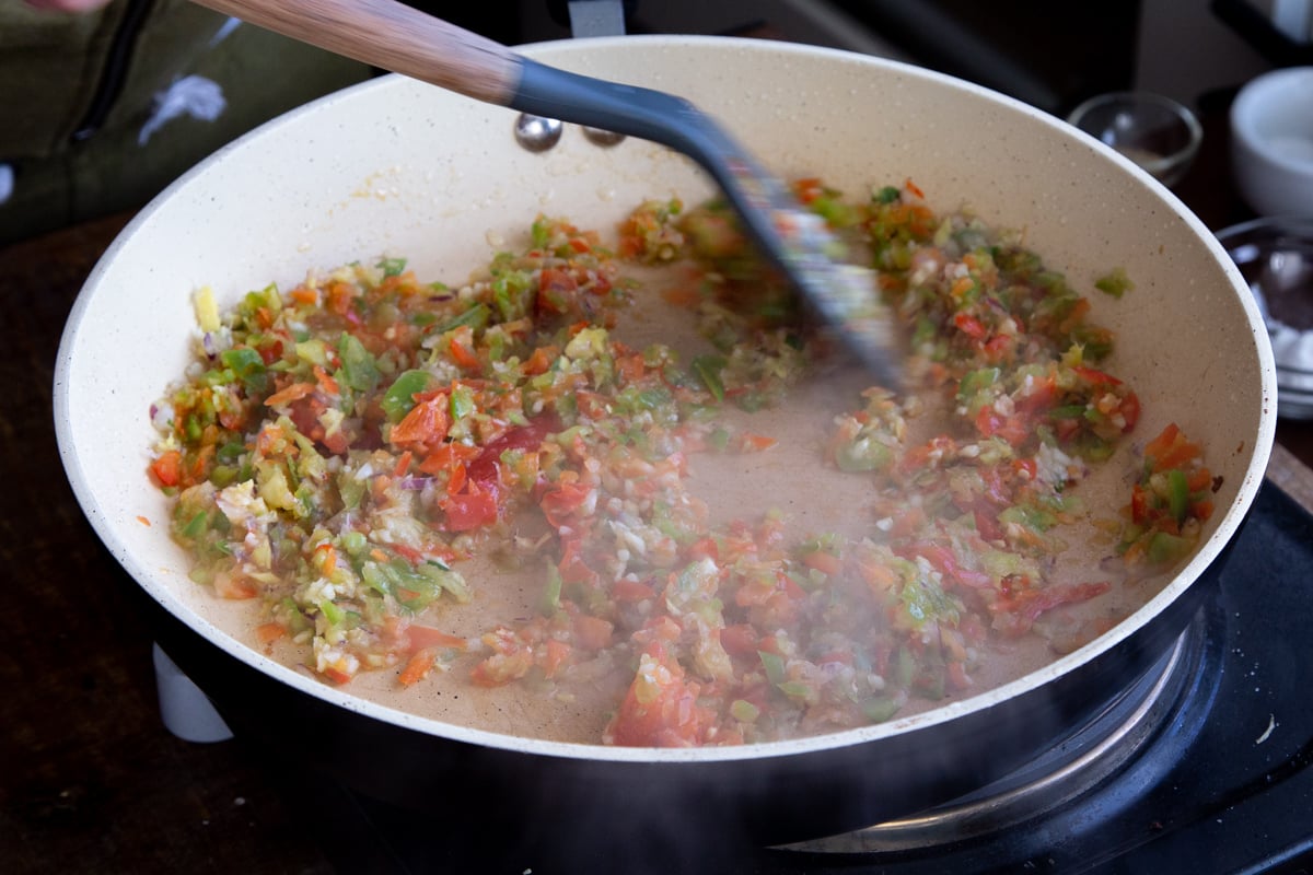 chopped bell pepper, ginger and garlic being fried in a pan