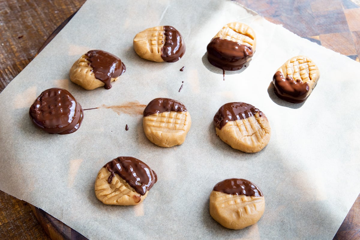 no bake peanut butter cookies dipped in melted chocolate on a sheet of parchment paper