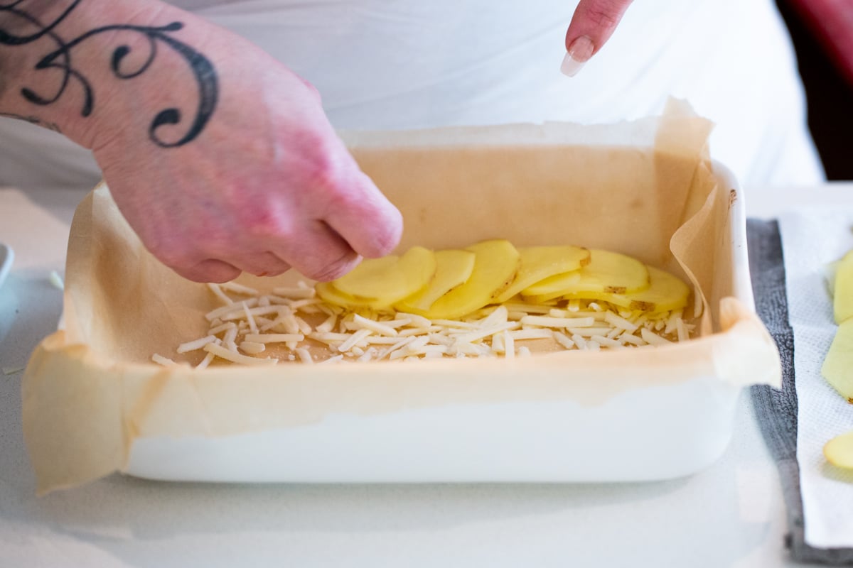 sliced potato with grated cheese in a casserole dish