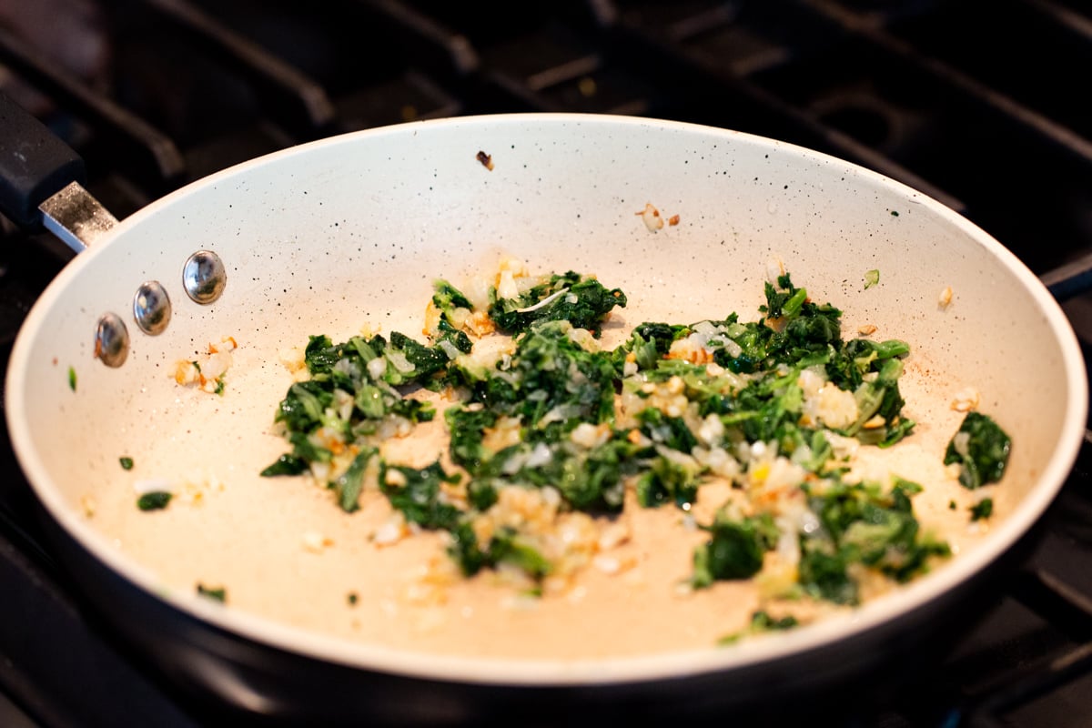 minced onion and chopped spinach in a sauteeing pan