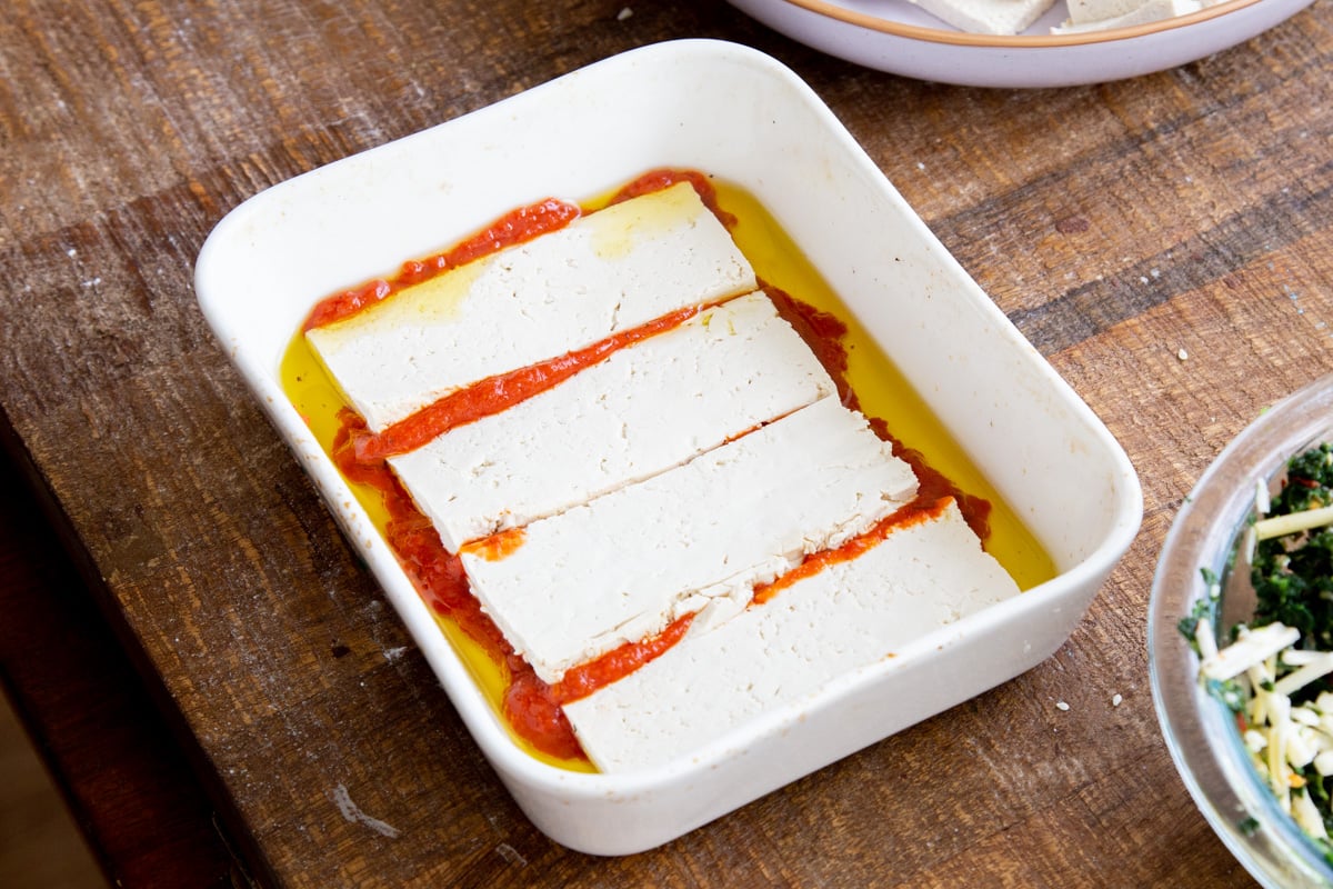 tofu slices in olive oil and marinara sauce in a small casserole dish