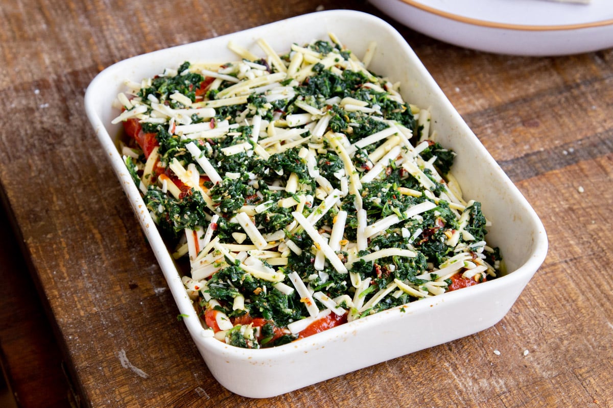 tofu lasagna being assembled in a white casserole dish