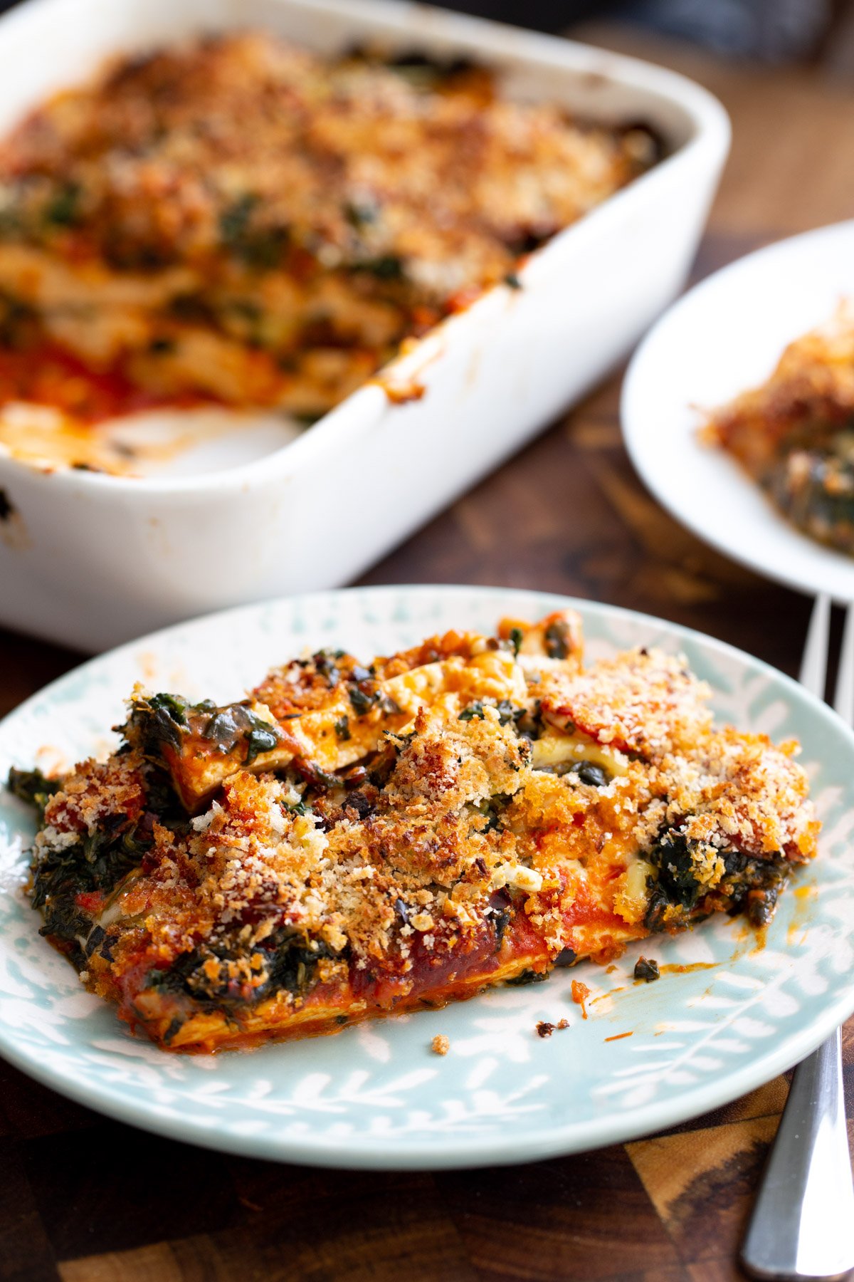 a serving of tofu parmesan bake on a blue plate with breadcrumb topping