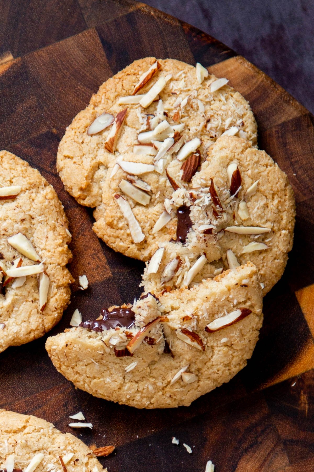 halved vegan almond joy cookies with half melted chocolate chunks peaking out on a wooden board