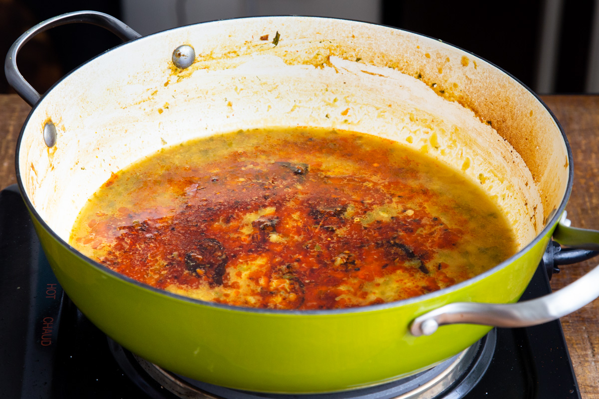 seasoned oil being poured into a sauteeing pan with chataka dal