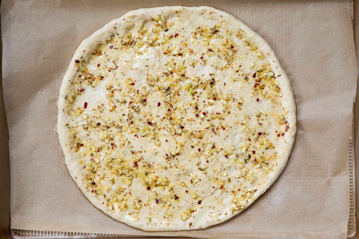 rolled out pizza dough on a baking sheet topped with olive oil and sprinkled with everything bagel seasoning