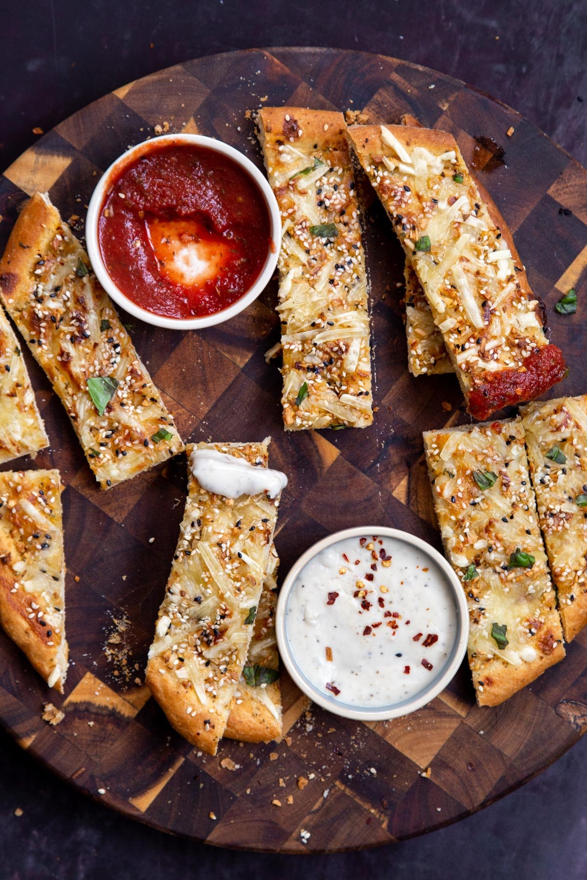 vegan cheese sticks sprinkled with everything bagel seasoning served with dips on a wooden board