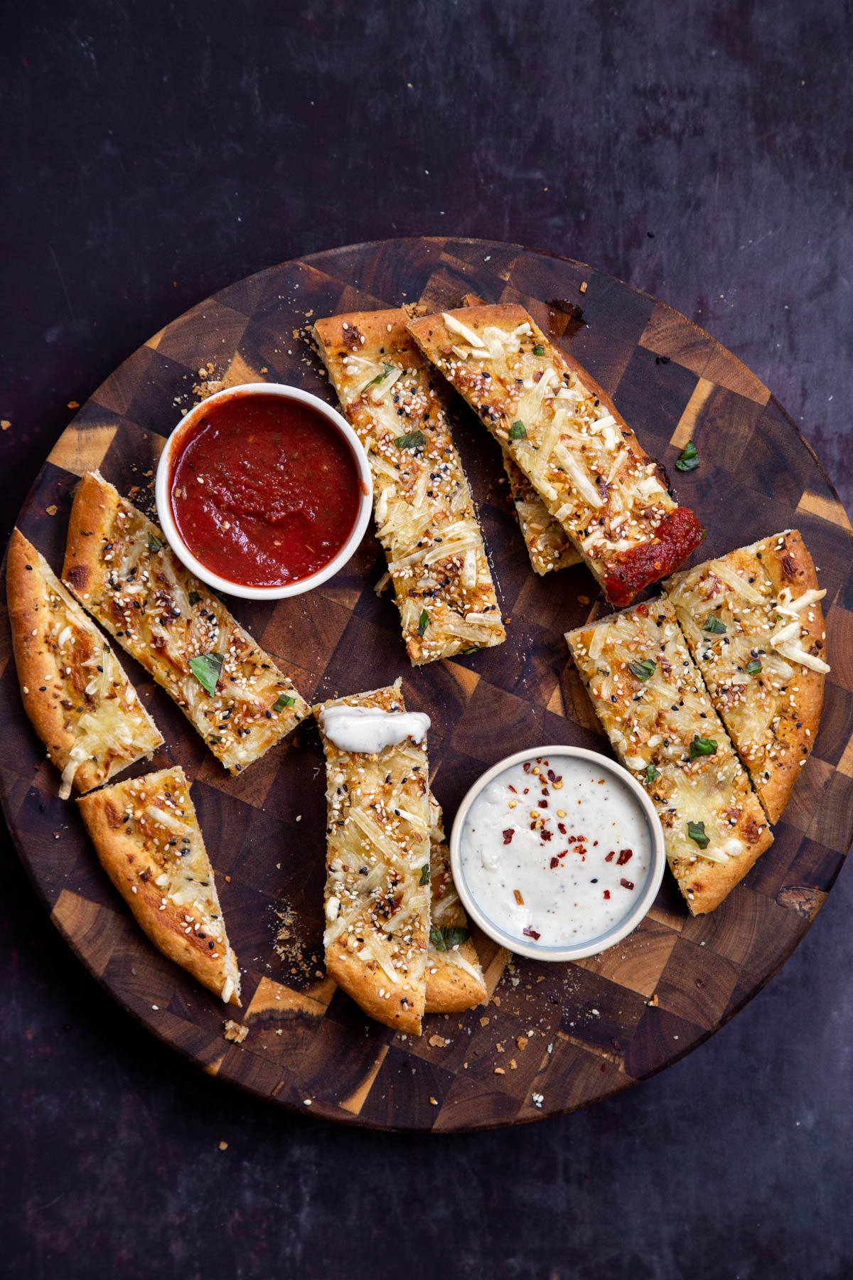 vegan cheesy garlic bread sticks served with dips on a wooden board