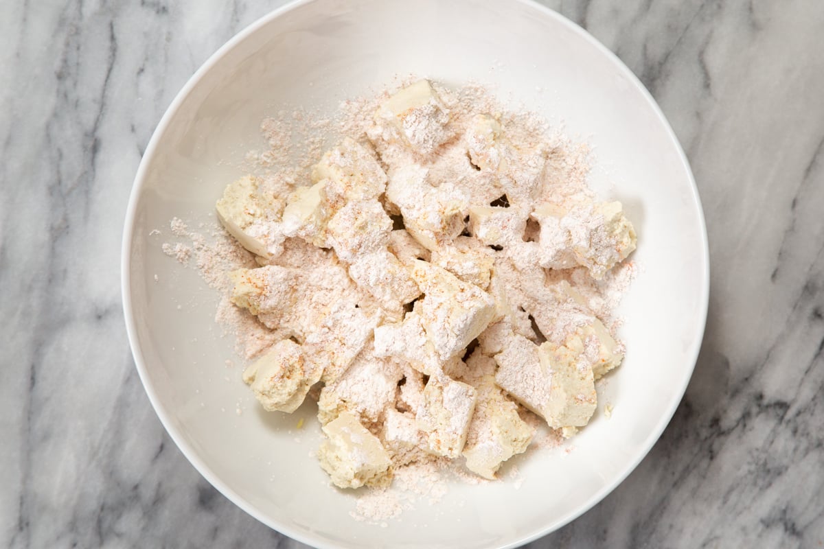 torn up tofu in a white bowl coated with spiced cornstarch