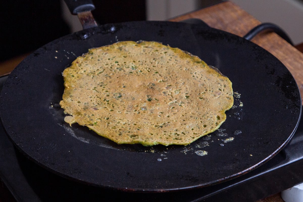 vegan lentil pancake being flipped in a black skillet