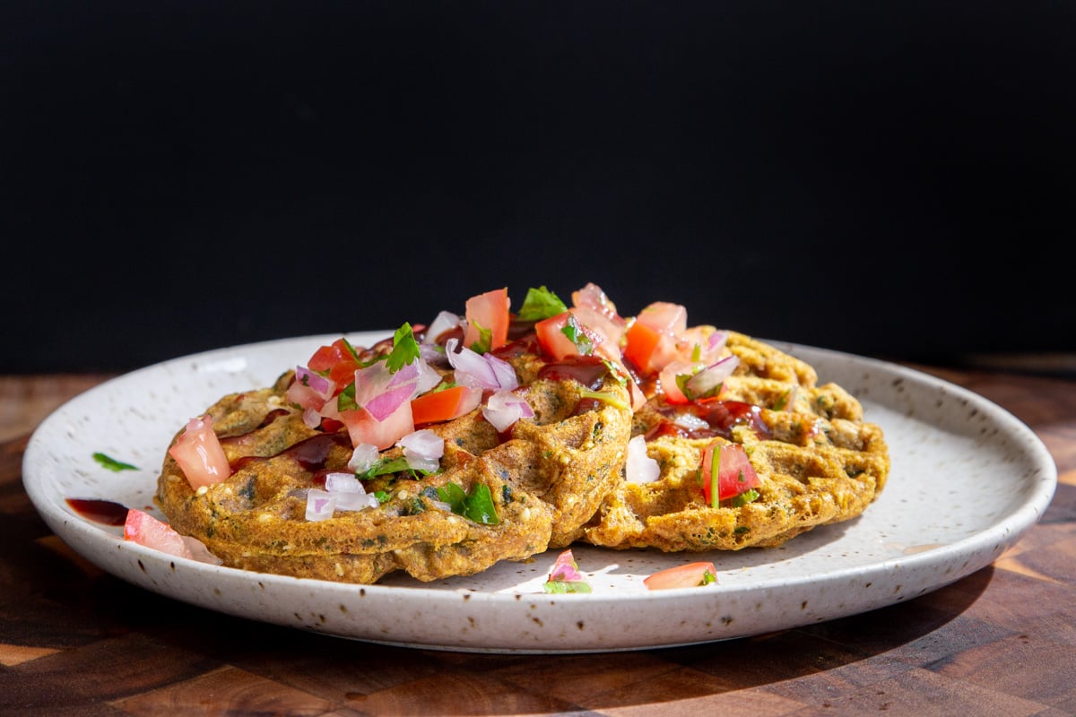 two vegan lentil flour waffles topped with pico de gallo on a white plate