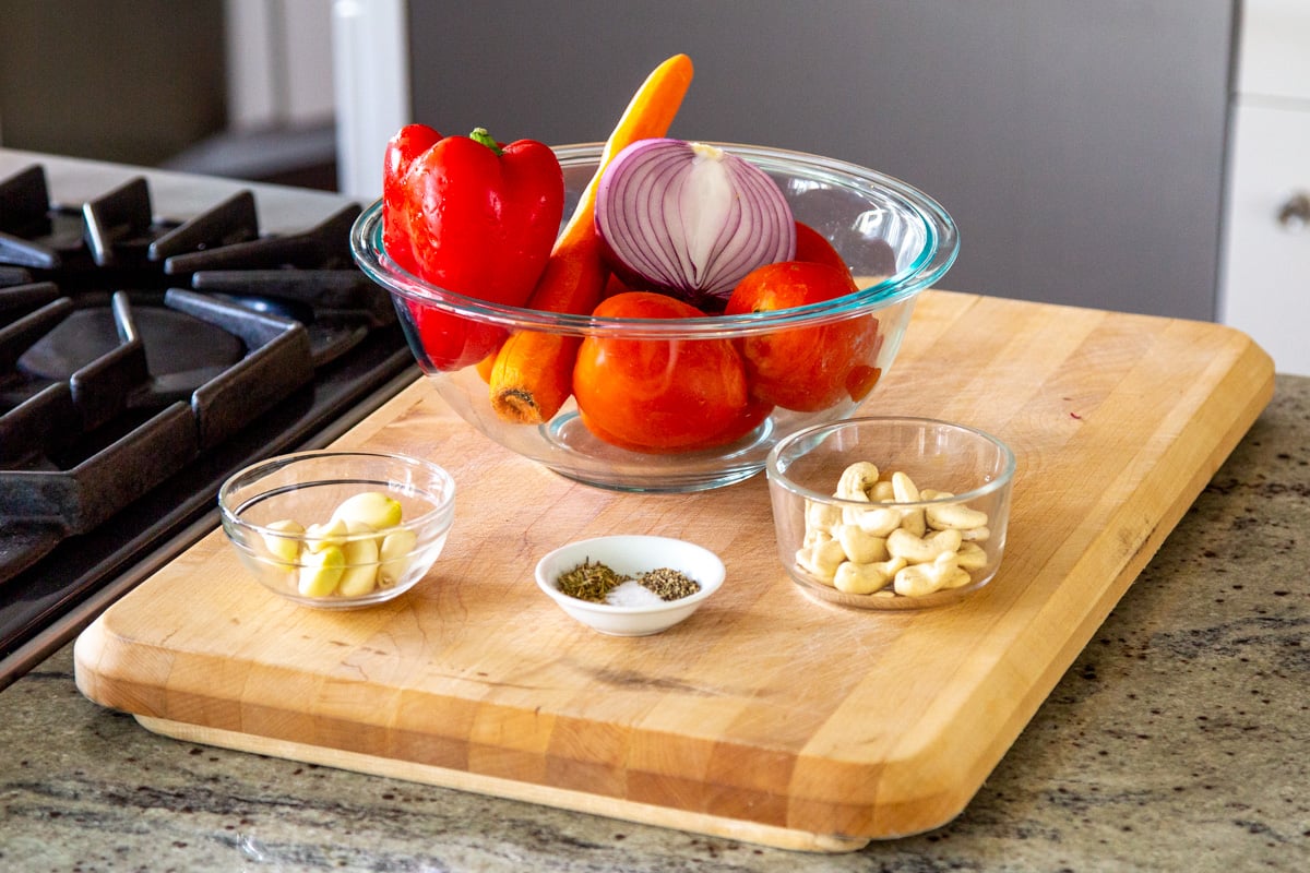 ingredients for making roasted tomato soup on a wooden board