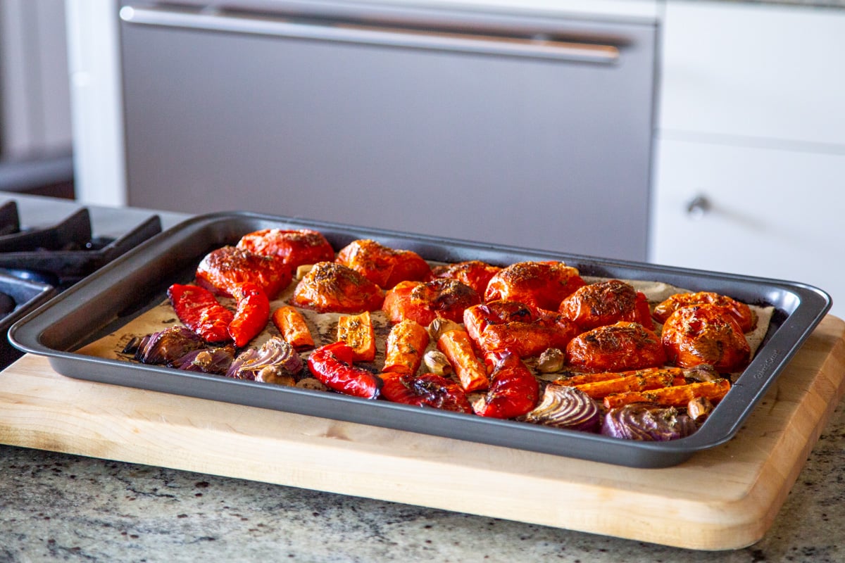 roasted bell peppers, tomatoes, garlic and onions on a baking sheet