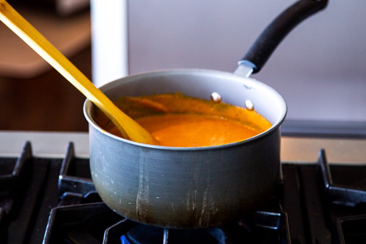 a pot with roasted tomato soup on a gas stove
