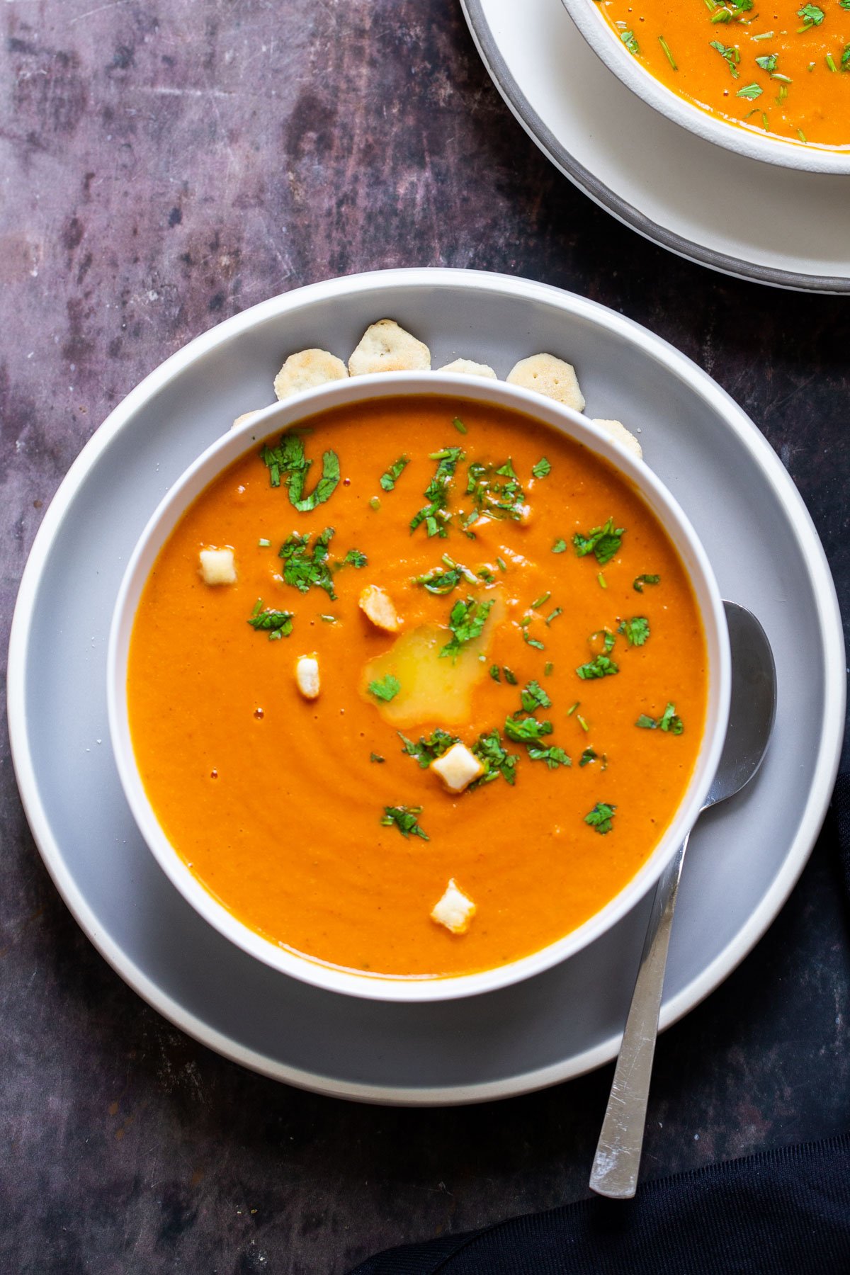 a plate of vegan roasted tomato soup with a spoon on the side