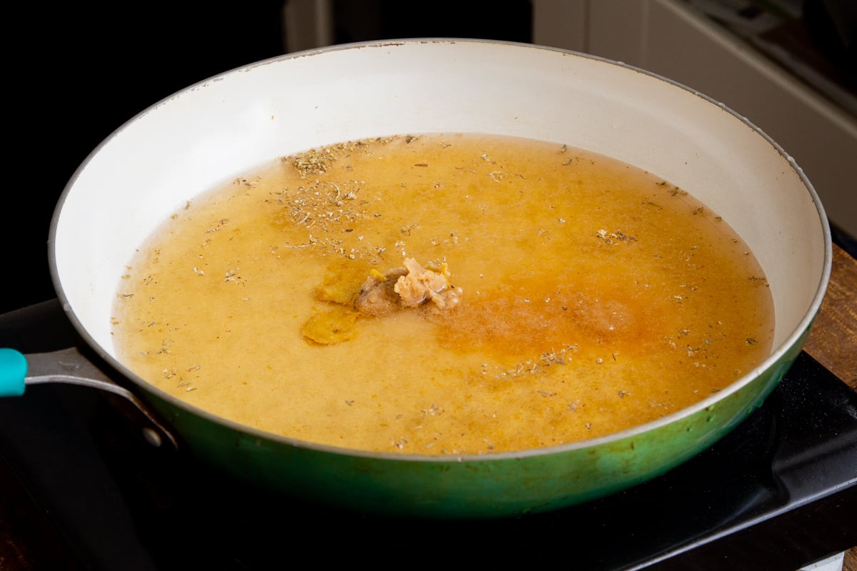a skillet with broth and miso paste heating on the stove