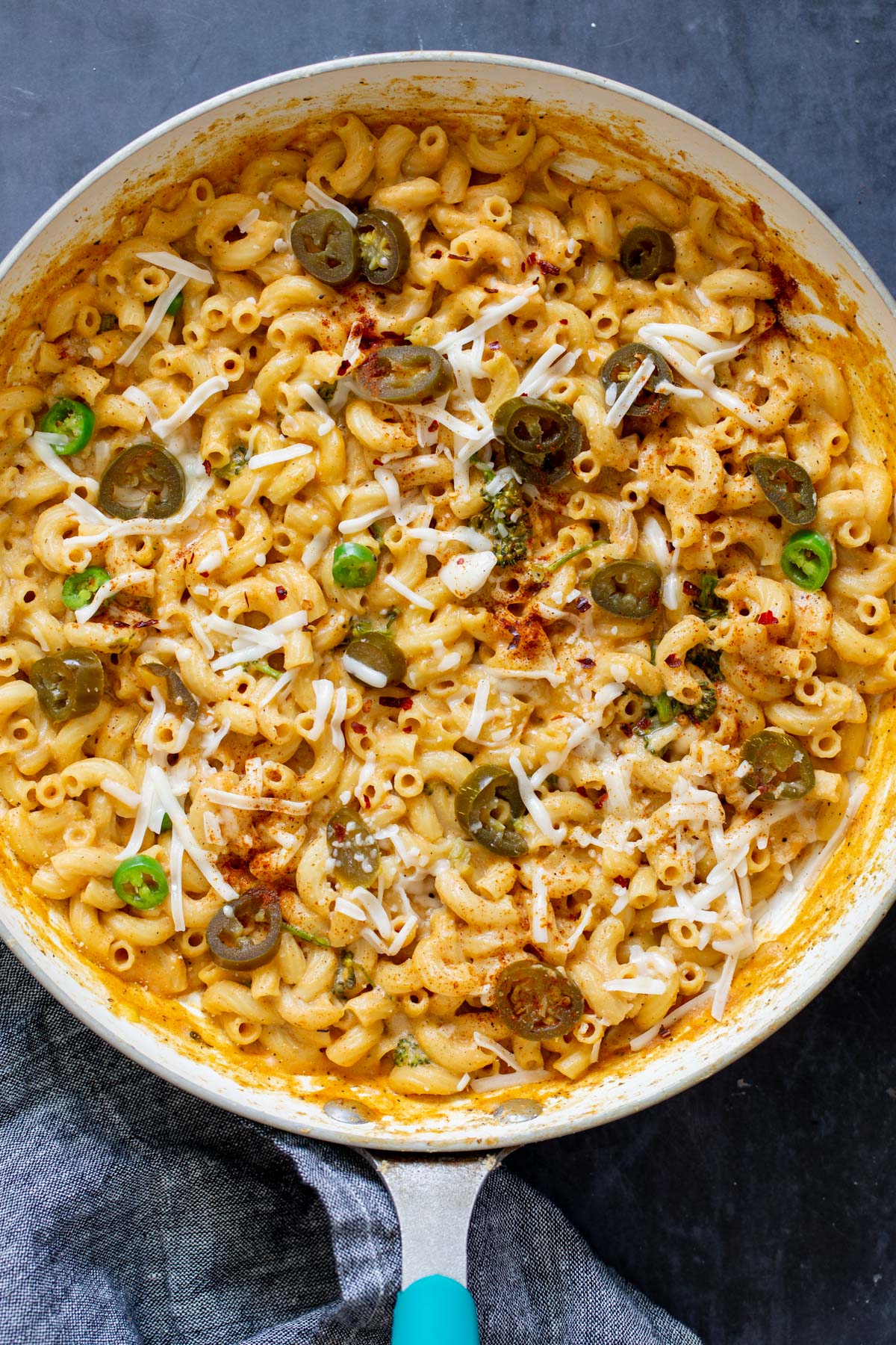 overhead shot of a skillet of vegan jalapeno mac and cheese topped with jalapeno slices and shredded cheese