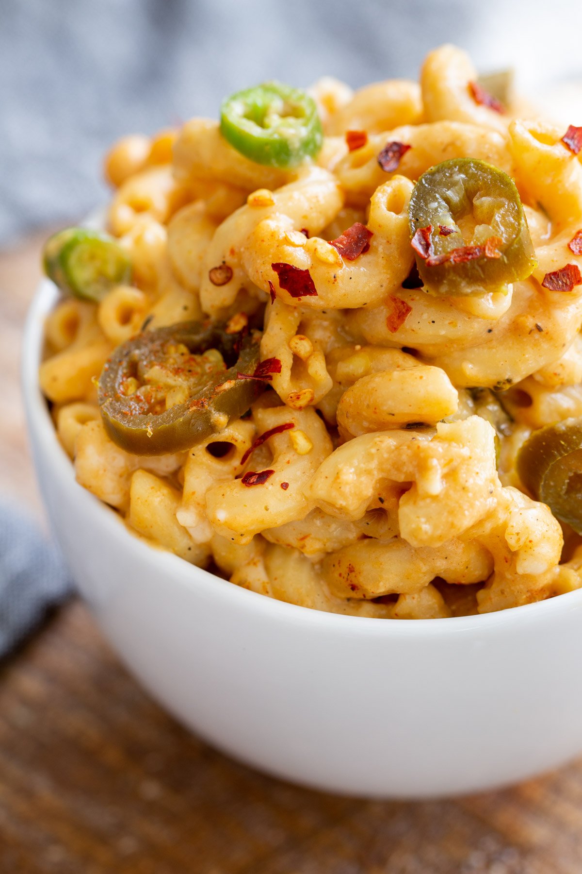 a serving of vegan mac and cheese topped with jalapenos in a white bowl