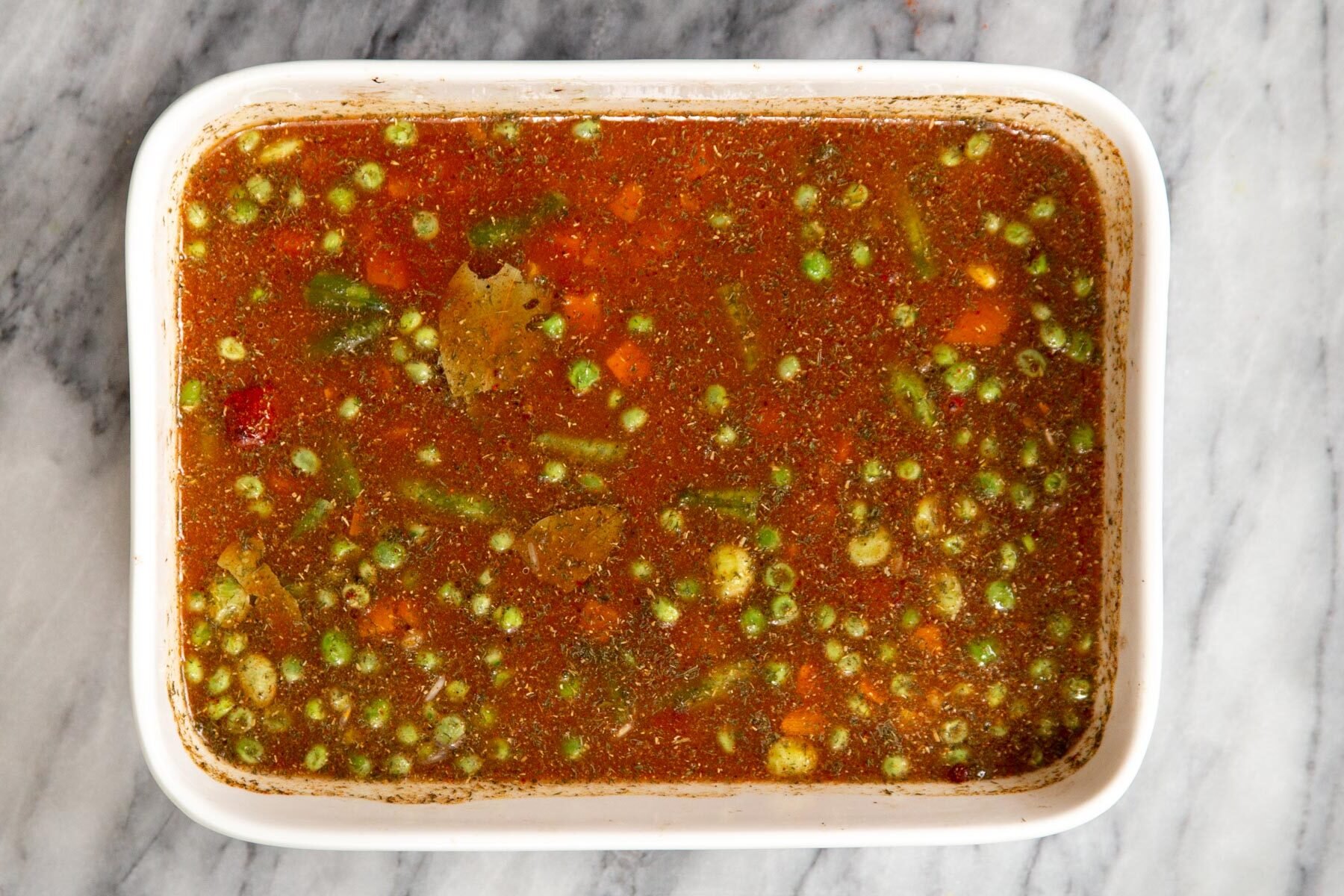 a white casserole dish with baked rice ingredients ready for baking