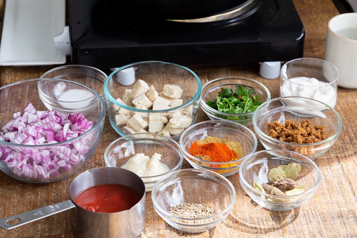 ingredients for making vegan balti chicken on a wooden chopping board
