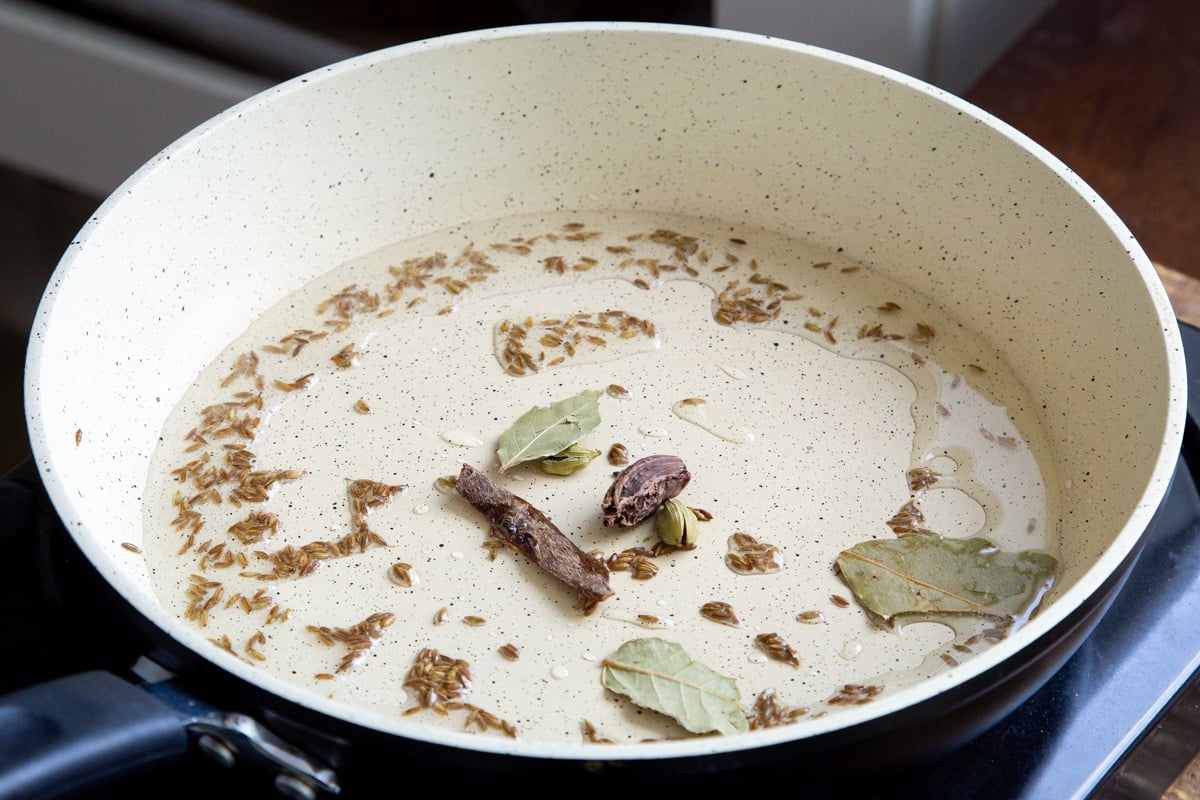 a sauteeing pan with cumin seeds and bay leaves