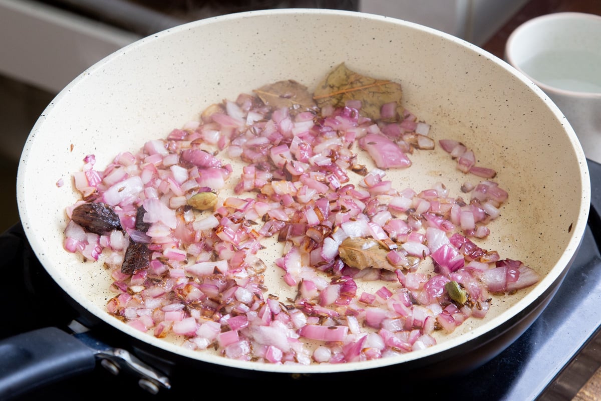 sauteed onions and whole spices in a pan