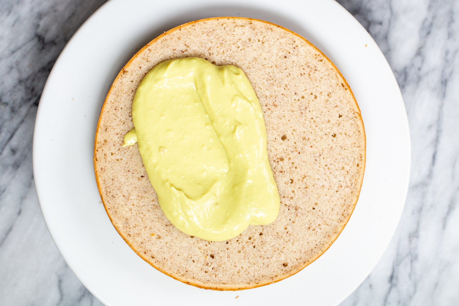 vegan custard being spread on a cake layer