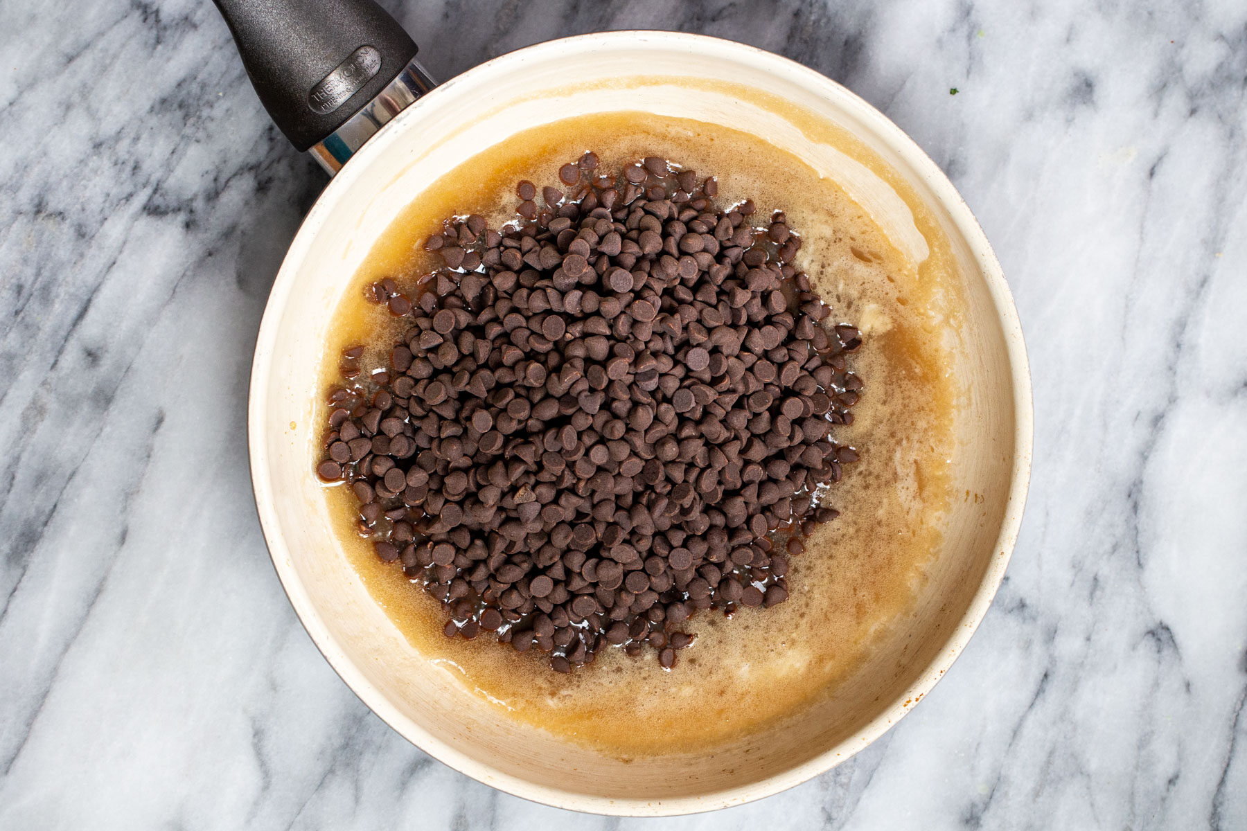 chocolate chips melting with coconut cream in a sauteeing pan
