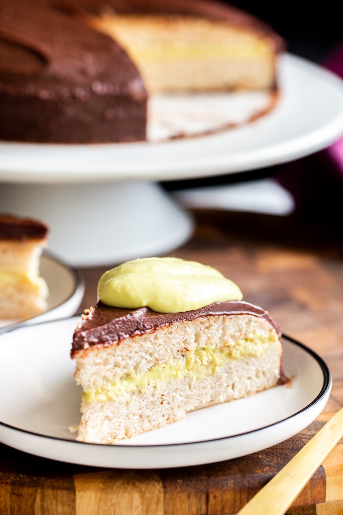 a slice of vegan boston cream pie topped with homemade vegan vanilla custard