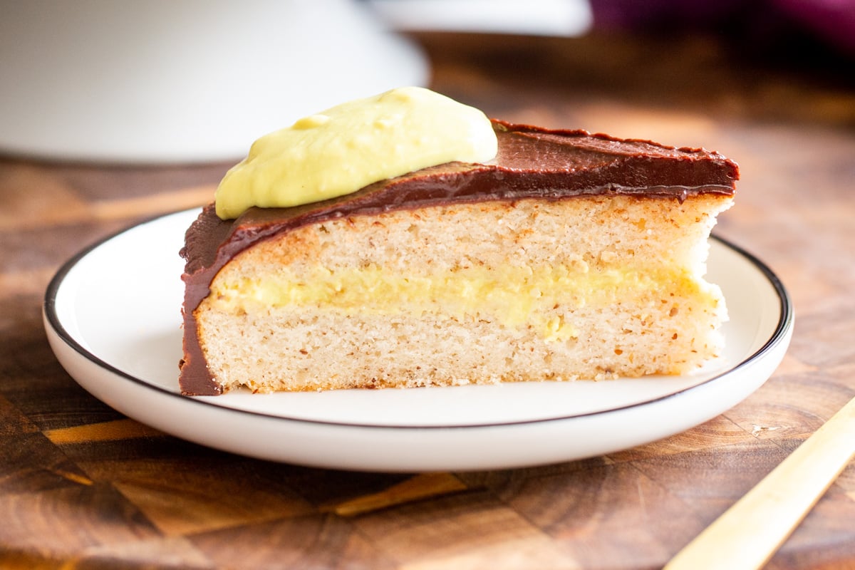 side view of a slice of boston cream pie cake on a wooden board