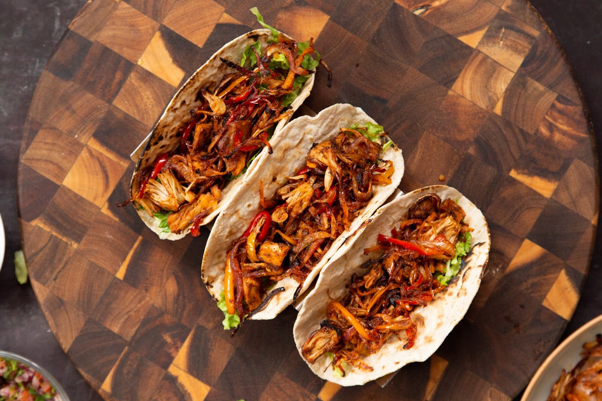 three jackfruit tacos with chopped lettuce and baked marinated vegan taco meat