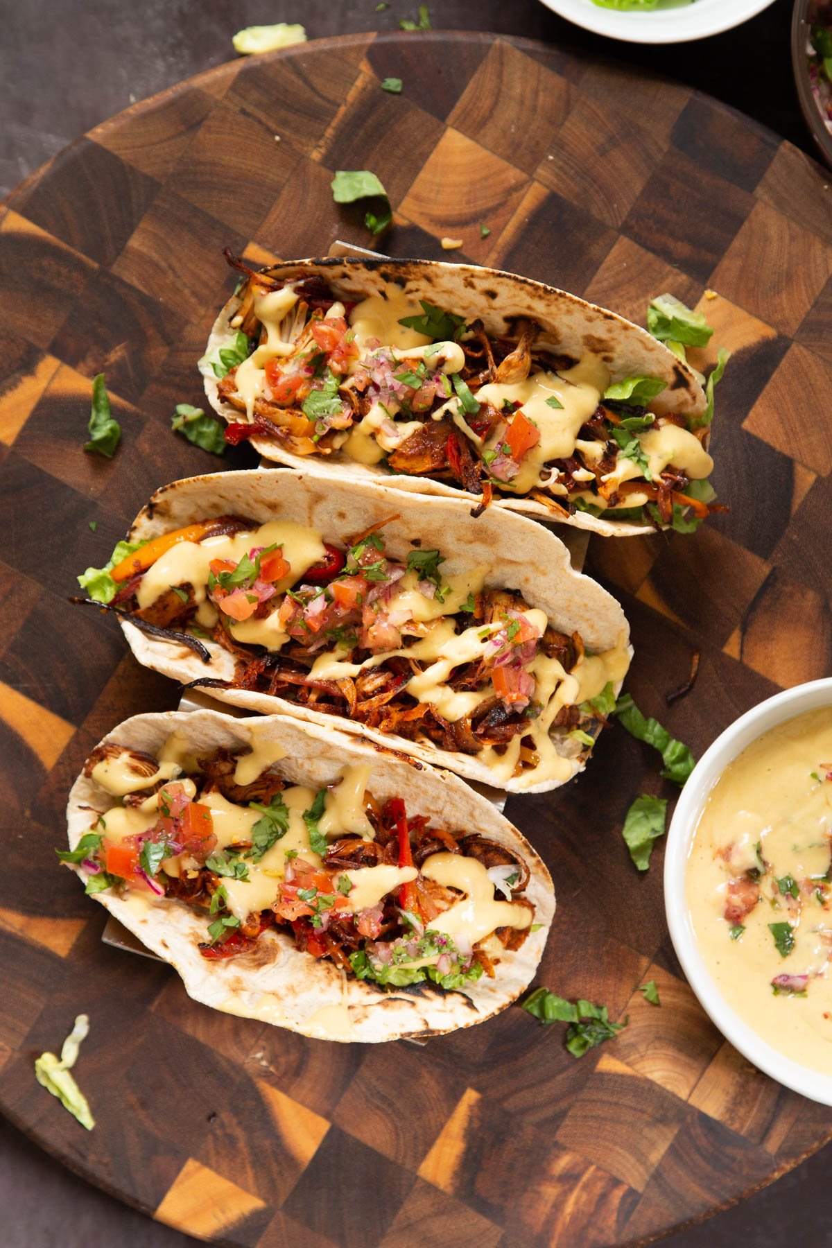 three vegan jackfruit tacos topped with queso and cilantro