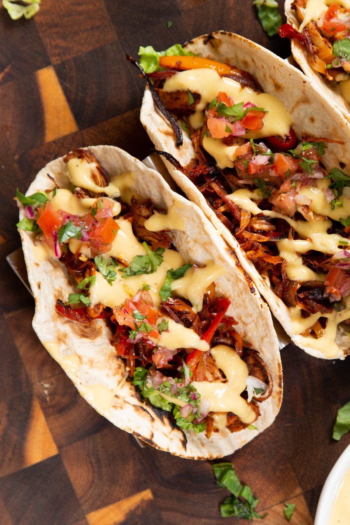 two vegan jackfruit tacos topped with vegan queso and cilantro