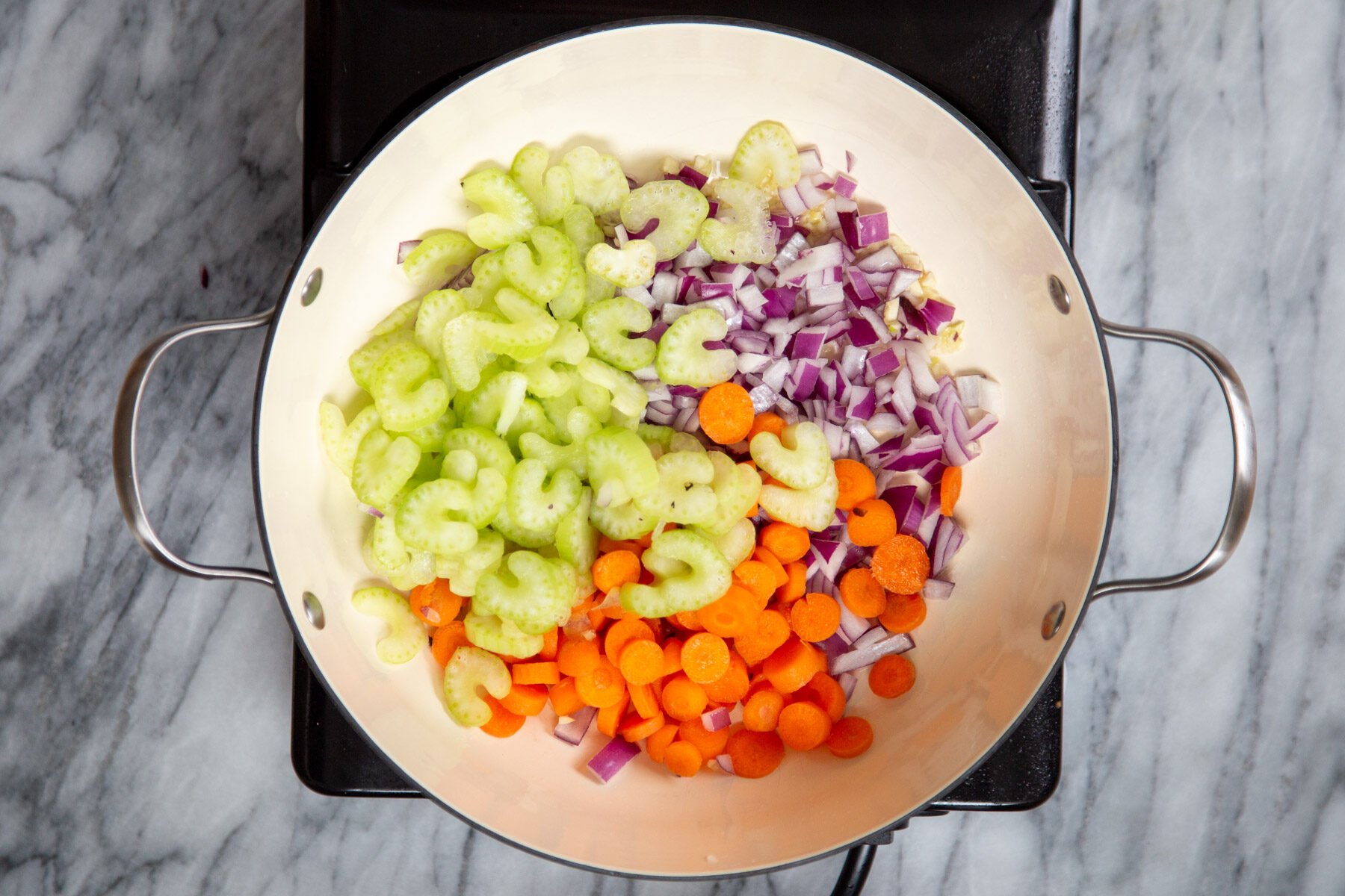celery, carrots and onions in a sauteeing pan