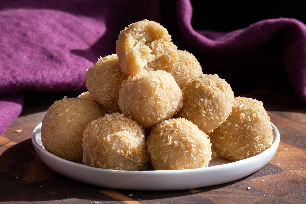 vegan lemon coconut energy snack bites on a small plate with a truffle with one bite taken