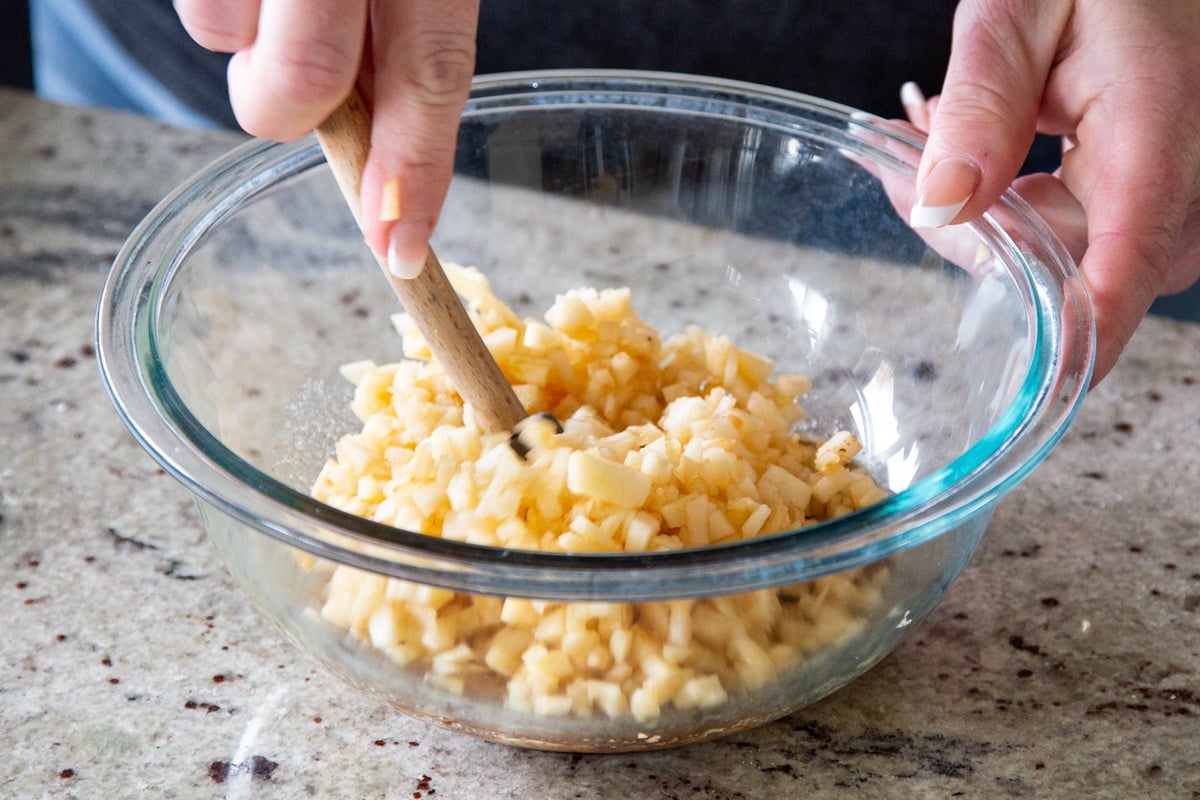 apple chunks being tossed with maple syrup
