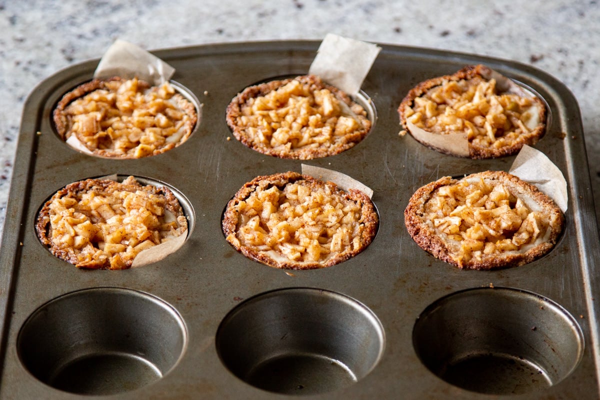 freshly baked vegan apple mini cheesecakes cooling down in a muffin tin